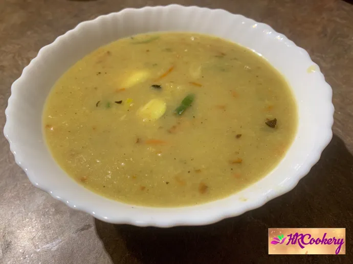 Sri Lankan rice porridge (Kenda) served warm in a white bowl on a kitchen counter.
