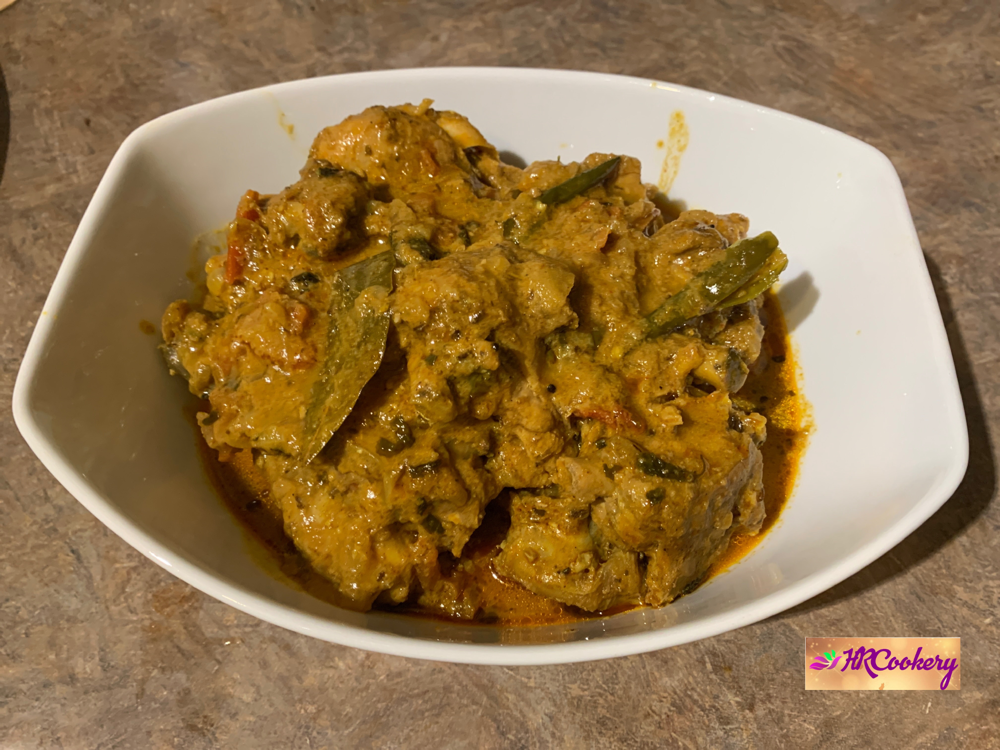 Authentic Indian chicken curry with yogurt and spices served in a bowl, garnished with fresh coriander and ginger.