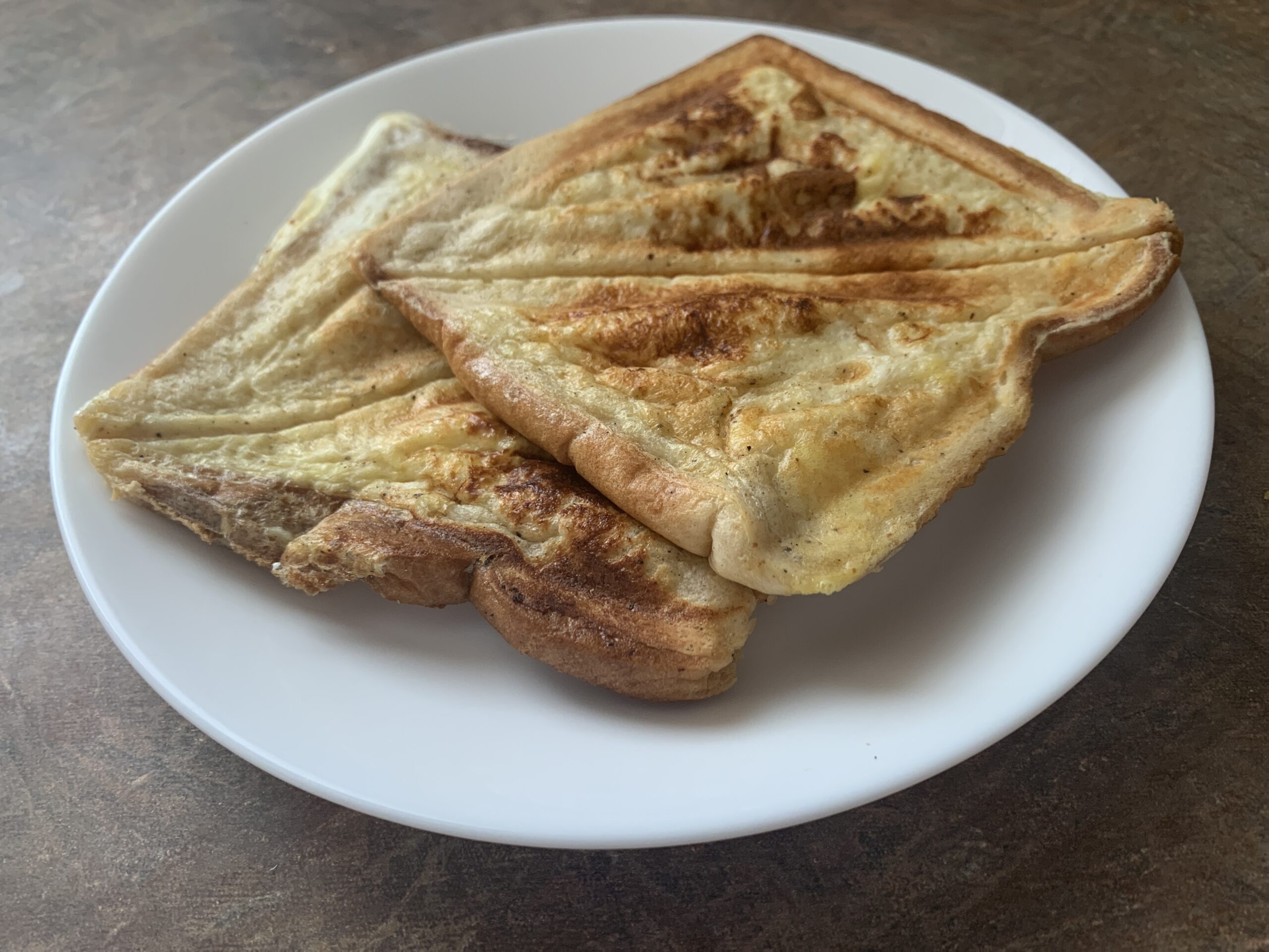 Delicious French toast sandwiches stacked with layers of sweet cream cheese and berry filling, adorned with powdered sugar and fresh berries on the side.