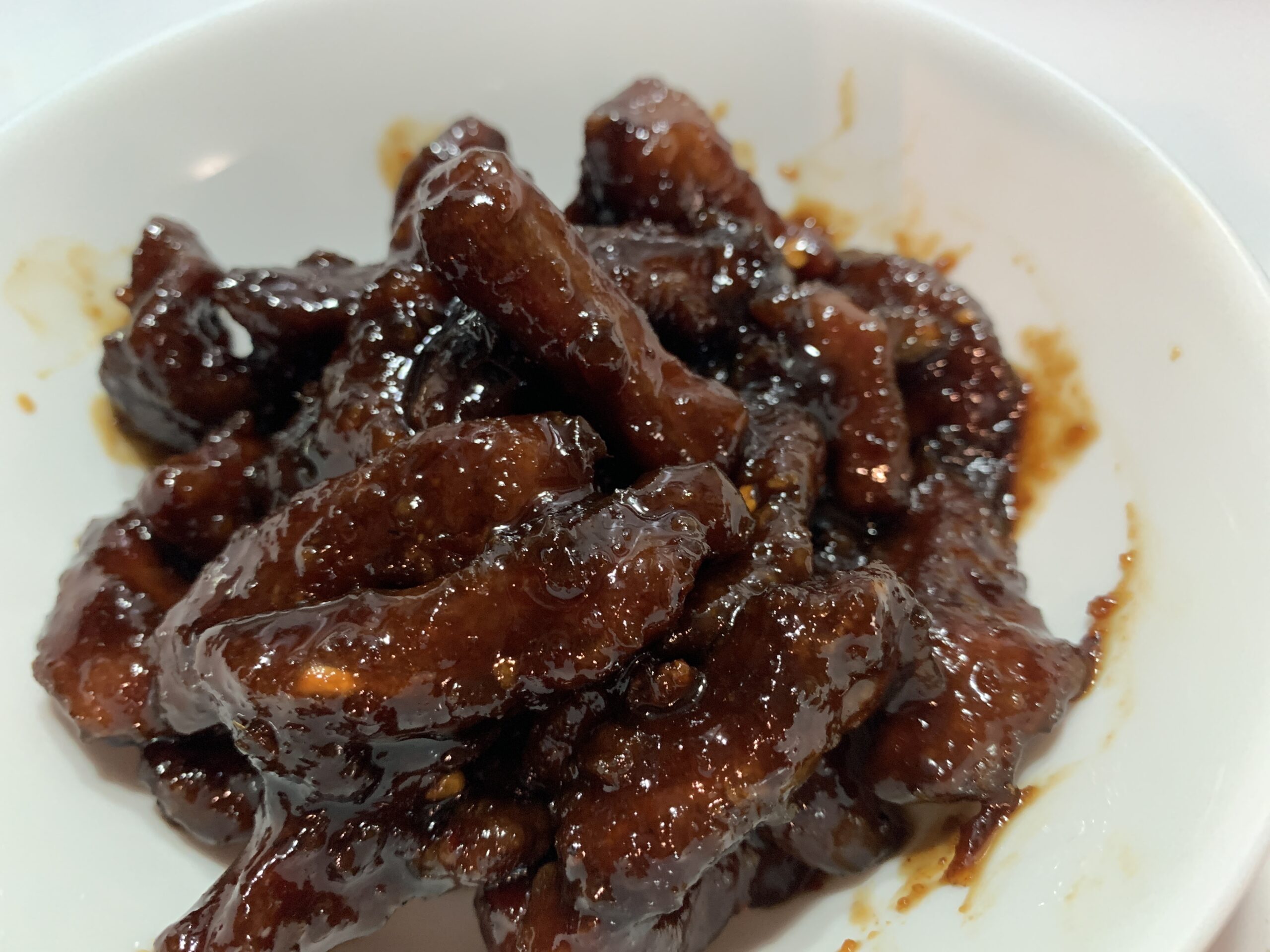 Plate of Mongolian beef stir-fry featuring tender strips of beef, green onions, and a glossy brown sauce served over steamed rice.