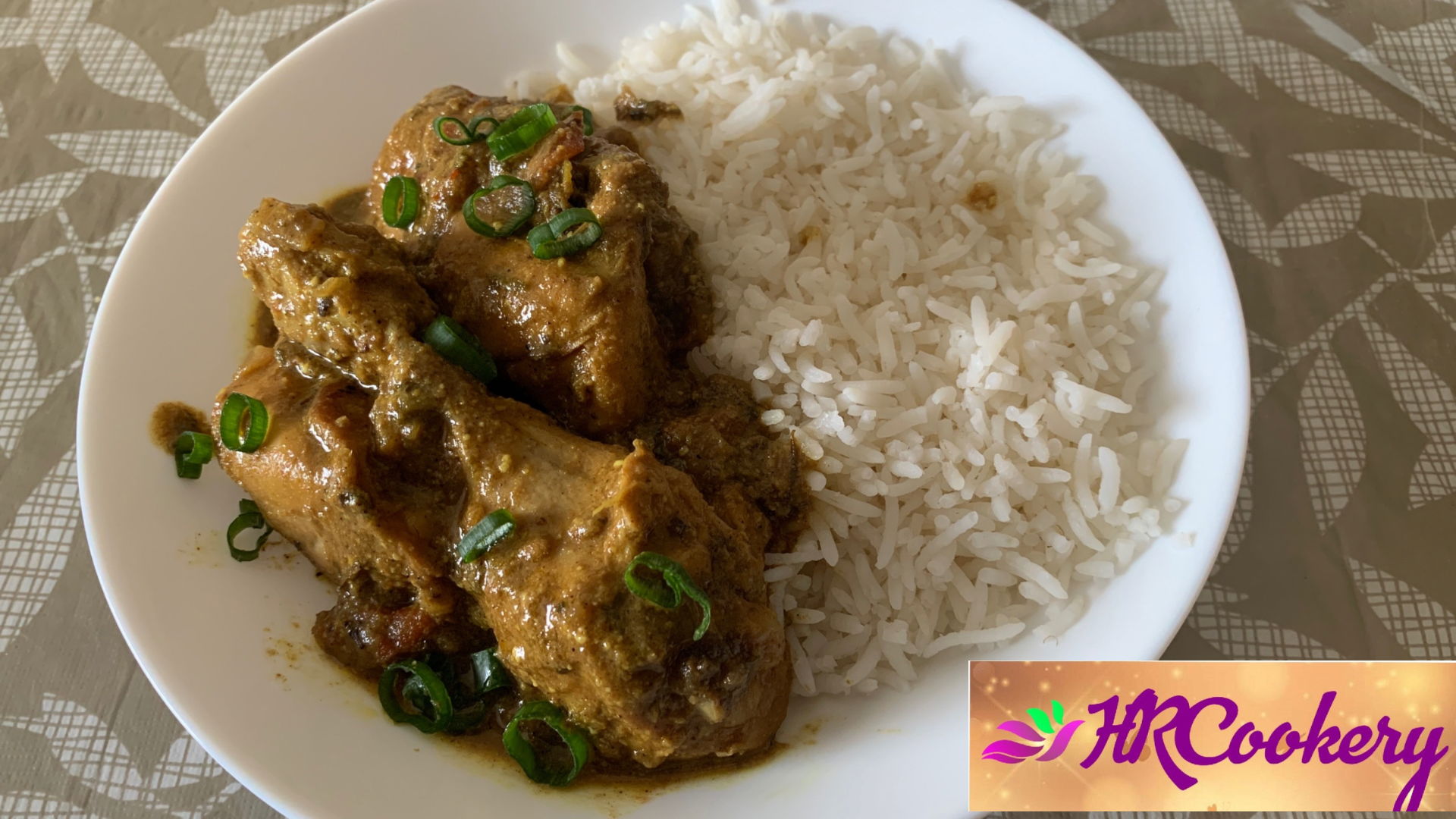 A plate of chicken curry in sweet chili sauce served over fluffy white rice, garnished with fresh cilantro and sliced red chili peppers.