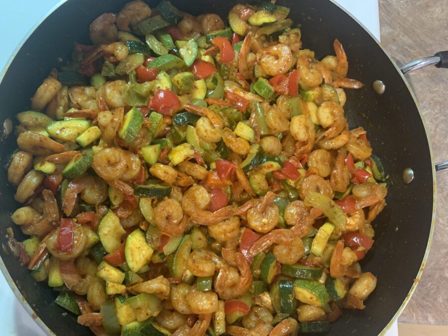 A colorful shrimp and vegetables skillet featuring sautéed shrimp, bell peppers, zucchini, and broccoli in a savory garlic sauce, garnished with fresh parsley.