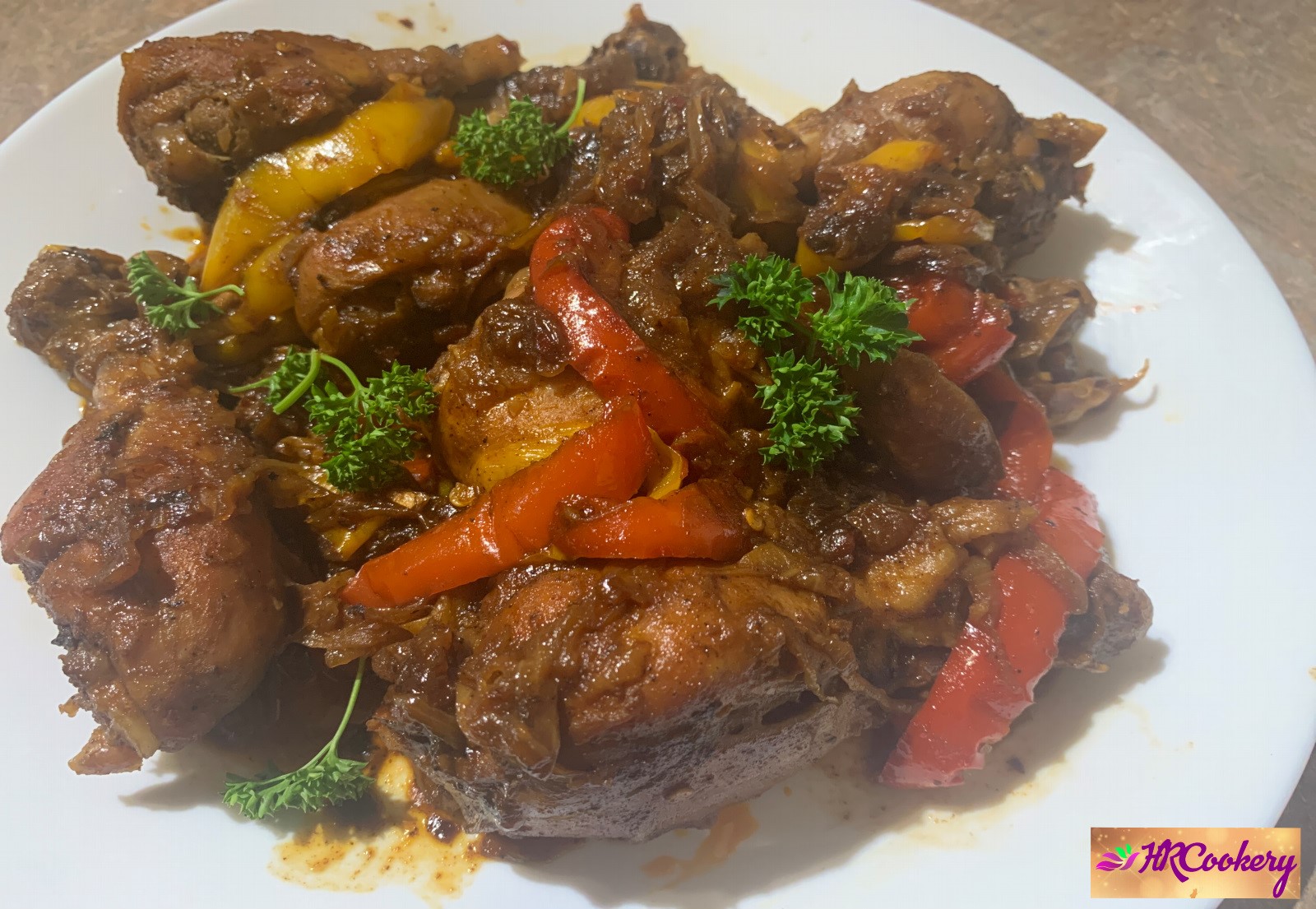 A plate of paprika chicken drumsticks garnished with fresh herbs, surrounded by colorful sliced bell peppers and drizzled with a savory sauce.