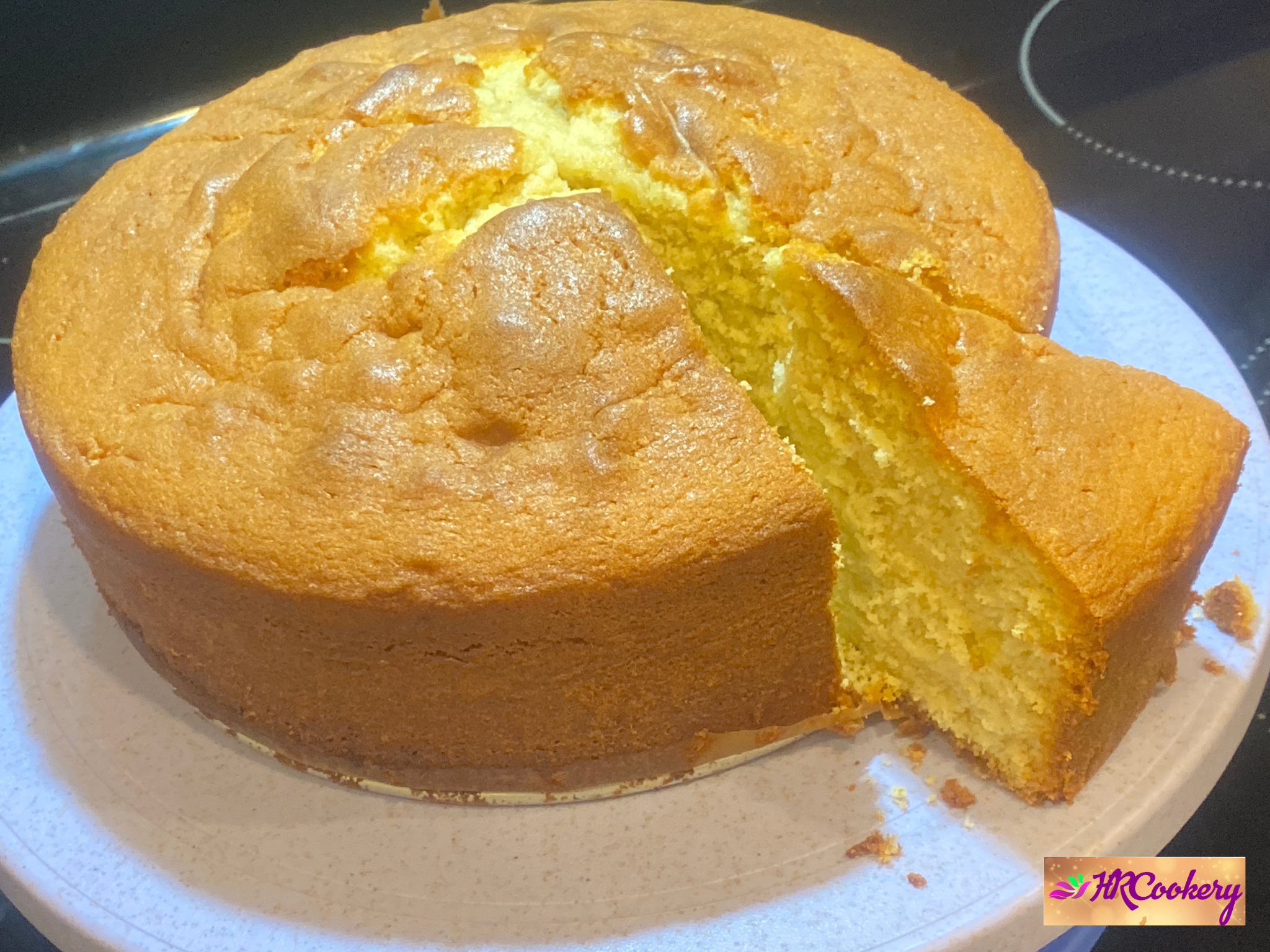 A golden slice of butter cake on a white plate, topped with a dusting of powdered sugar and garnished with fresh berries.