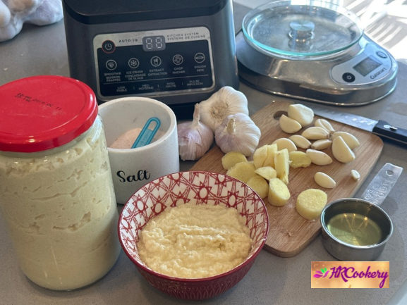 Homemade ginger garlic paste in a glass jar with fresh ginger and garlic cloves on the side