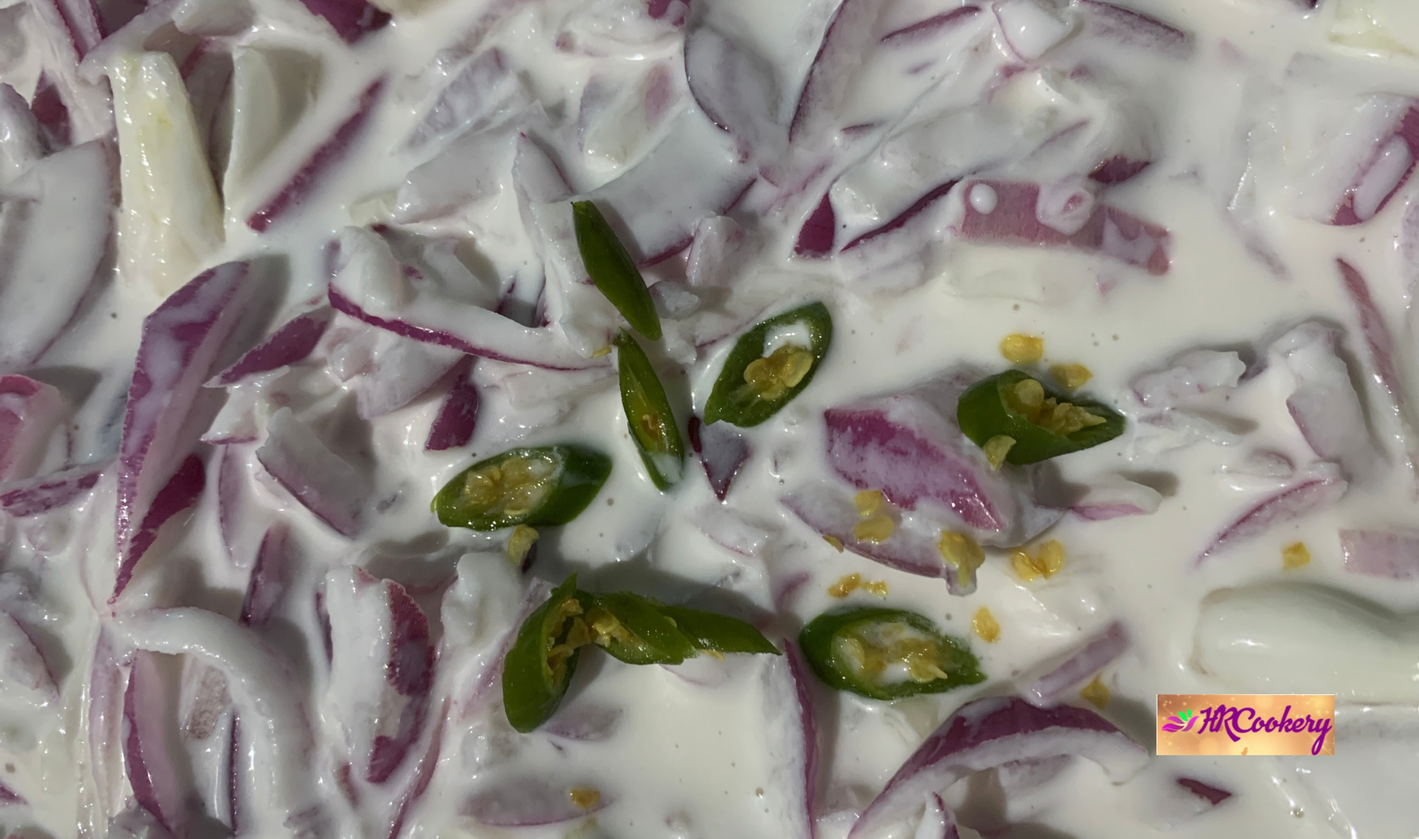 A fresh red onion salad in a white bowl, featuring thinly sliced red onions, and a sprinkle of herbs, drizzled with lemon juice.