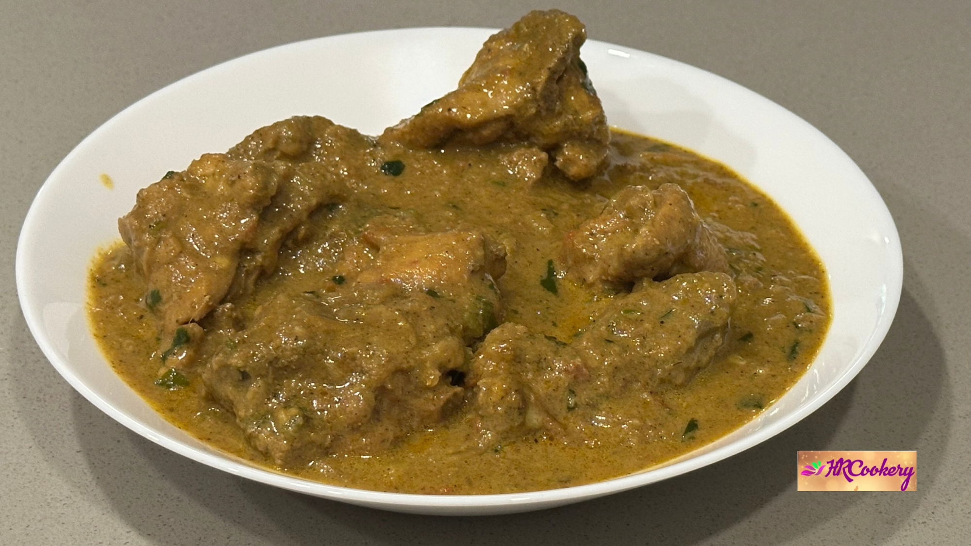Creamy coconut chicken curry served in a white bowl, featuring tender chicken pieces coated in a rich, spiced coconut gravy.