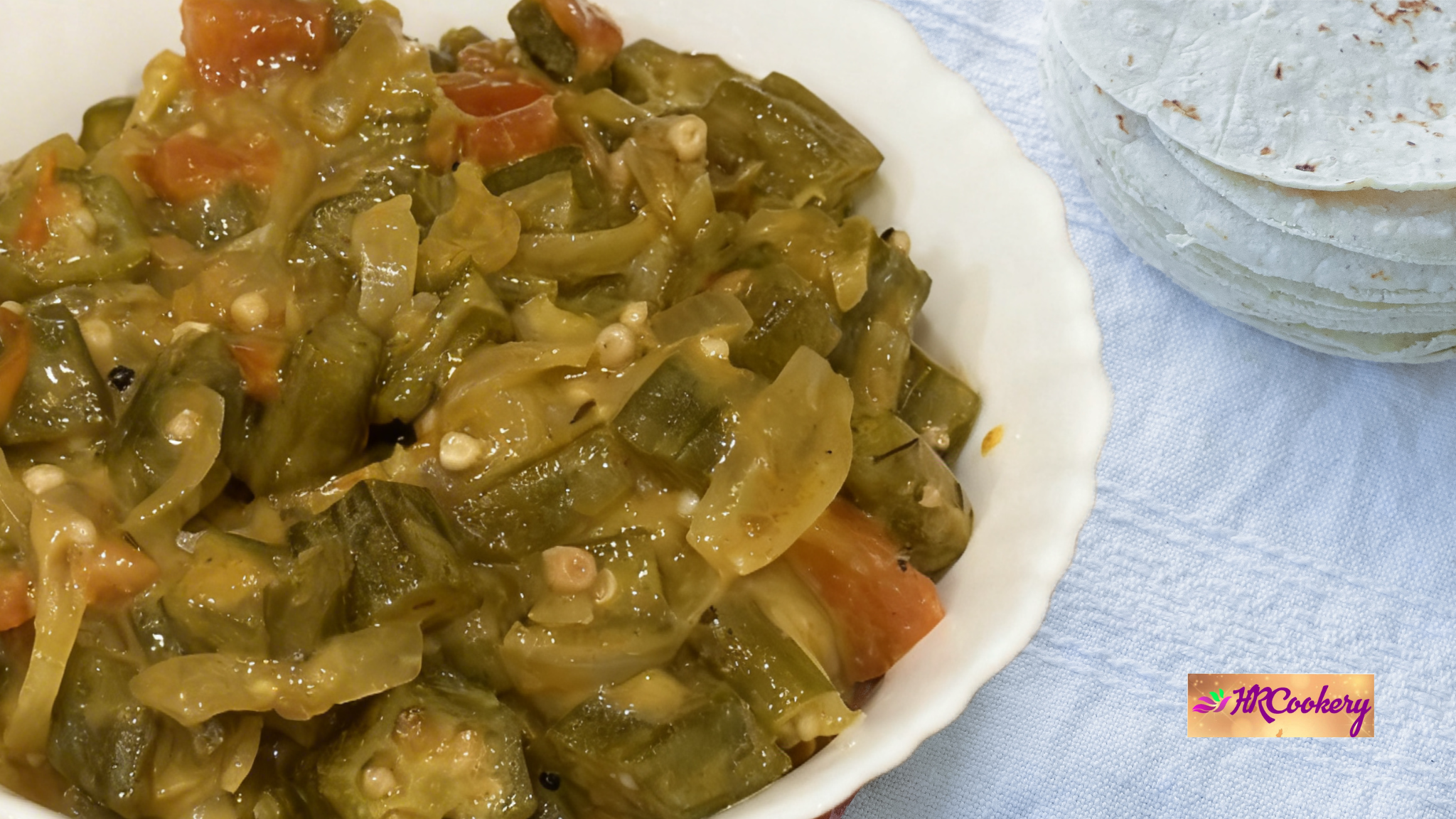Sri Lankan okra coconut curry with tomatoes and onions served in a white bowl with string hoppers on the side