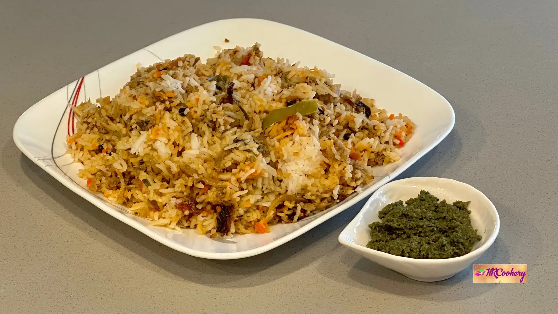 Tuna fish biryani served on a white plate with mint chutney on the side