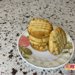 Freshly baked cream cheese cookies on a cooling rack, some sprinkled with powdered sugar.