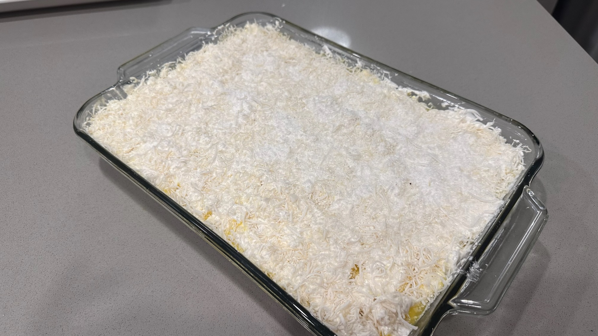 Custard and coconut marshmallow bars topped with shredded coconut in a 9x13-inch glass baking dish
